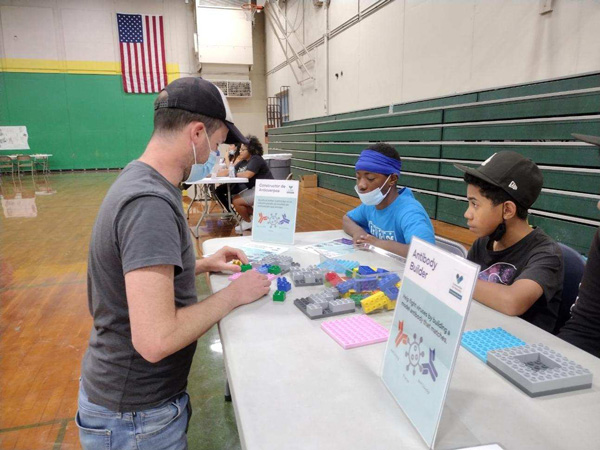 An adult is modeling a science activity consisting of antibodies and viruses