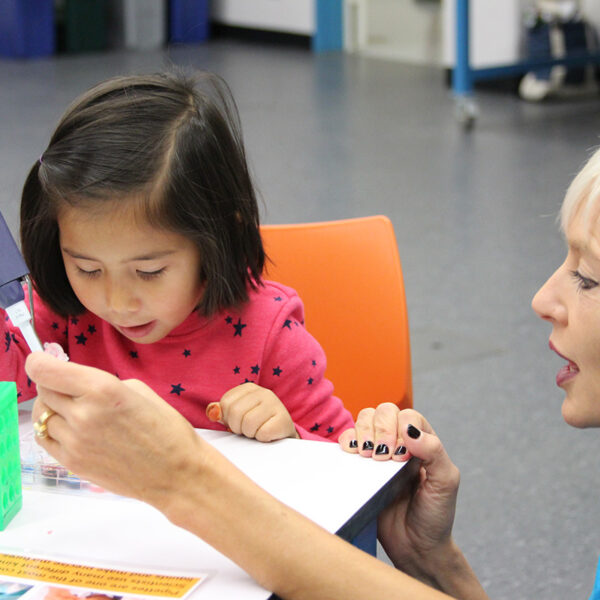 A Lawrence educator teaches a child how to use a pipette