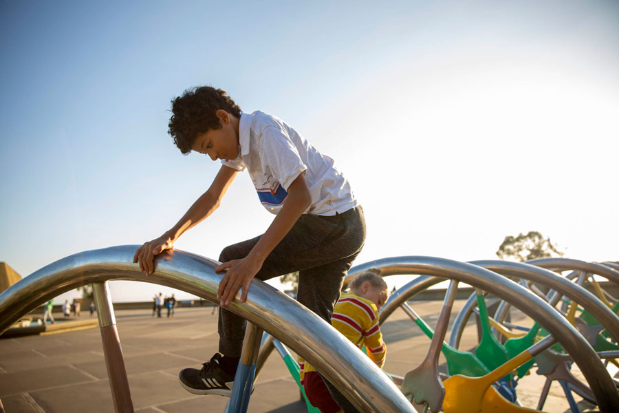A young person climbing on the DNA Sculpture on the plaza at The Lawrence