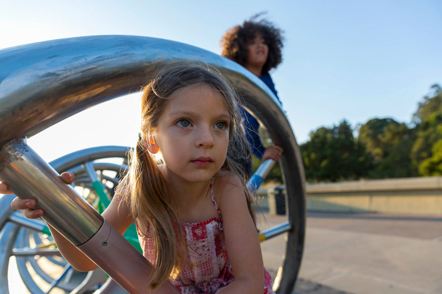 Two children climbing on the DNA Sculpture on the plaza at The Lawrence
