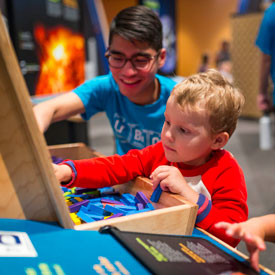 A volunteer and a child are exploring a science exhibit activity - Design Quest