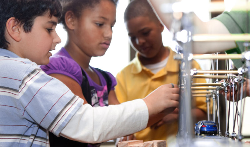 Three students participate in a building bridges activity