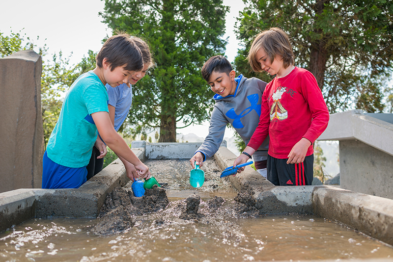A group of visitors experiment with sand on an erosion table