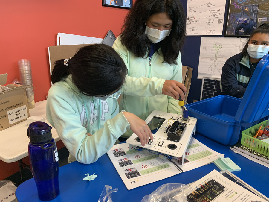 A camp leader and camper work on a solar project together