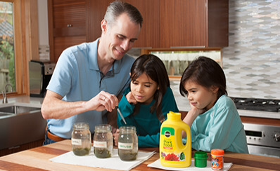 Two children and an adult examining jars of lake water.