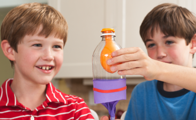 Two students building a lung out of a bottle and a balloon in a science experiment