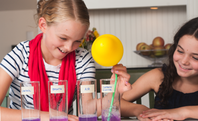 A young person holds a balloon in a science experiment about what's in your breath