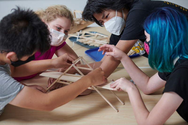 Four students are building a model bridge during a Teen Research Program