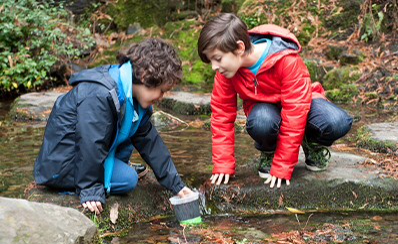 Two young people examining a lake.
