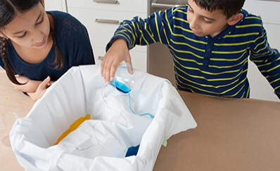 Two children learning how to make a lake for a science experiment.