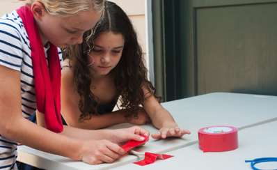 Two young people using tape in their science experiment about weak and strong bones