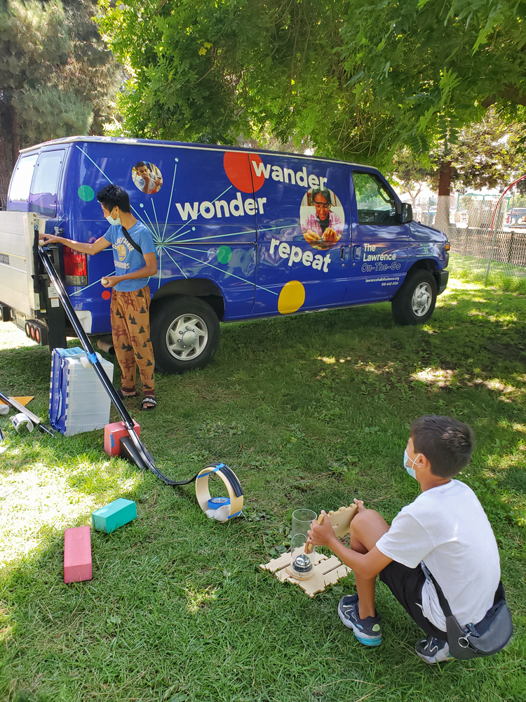 Two students are participating in a Lawrence On-The-Go activity outside using a ramp.