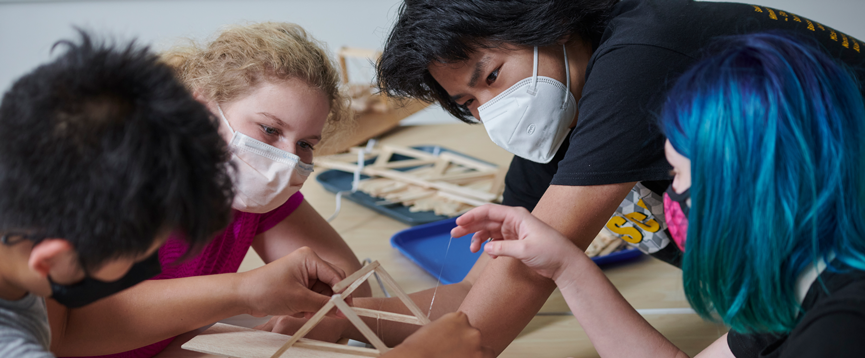 A group of students are working together to design a model bridge